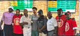 Group of people posing together in front of a scoreboard